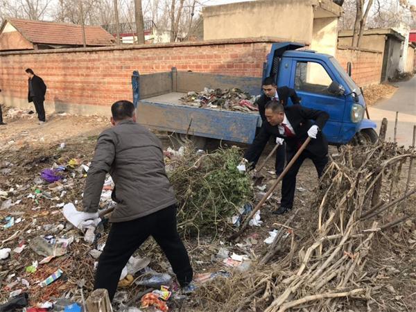 院长滕宝成帮助村民装垃圾。